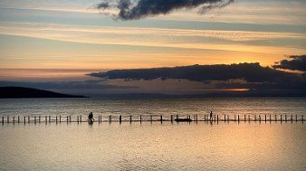 Swimmers on the causeway on a golden evening